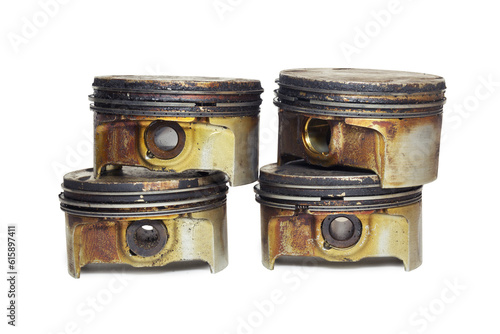car engine pistons, partially disassembled, worn out and dirty, in remnants of burnt oil. equipped with pressure rings, neatly piled. isolated on white background, with clipping path
