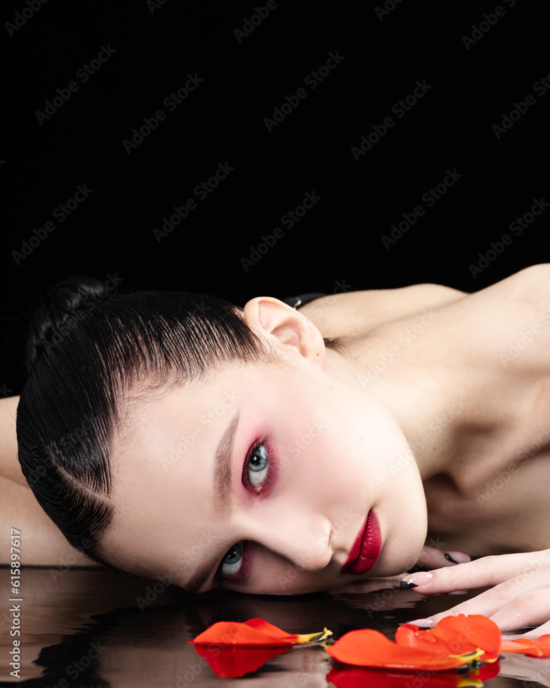 Beautiful girl in the reflection of water with floating petals