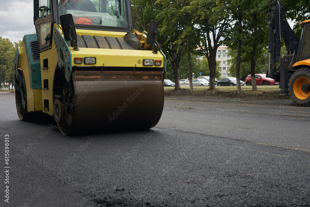 A road roller compacts the asphalt mortar on the road to be repaired. A road roller compacts the asphalt mortar on the road to be repaired.