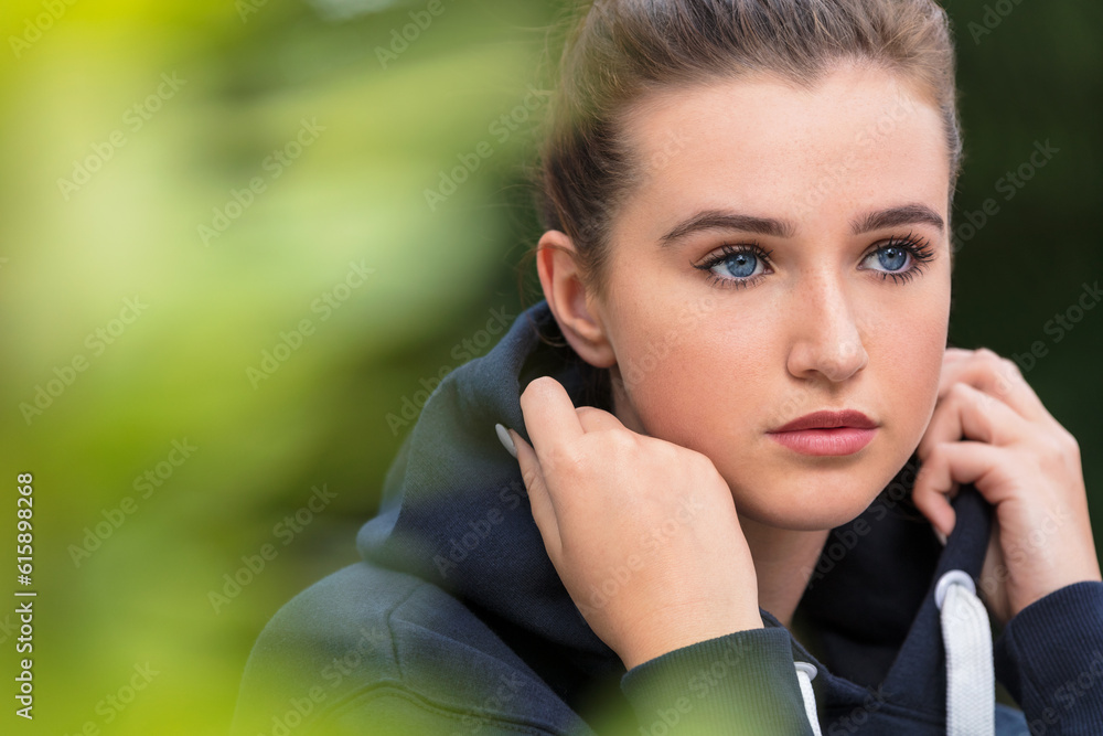 Beautiful girl teenager female young woman with blue eyes outside wearing dark blue hoody looking sad depressed or thoughtful Beautiful girl teenager female young woman with blue eyes outside wearing dark blue hoody looking sad depressed or thoughtful