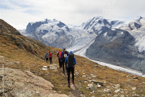 Panorama view with mountain Dufourspitze (left), Gorner Glacier, mountain Lyskamm (right) and group of mountaineers hiking towards mountain massif Monte Rosa in Pennine Alps, Switzerland photo