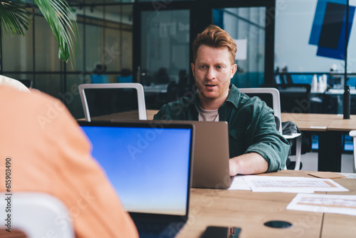 Positive man working on laptop while sitting at table