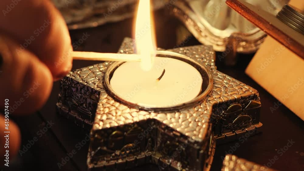 A woman's hand lights candles on the eve of Shabbat in candlesticks in the shape of a star of David. Medium plan A woman's hand lights candles on the eve of Shabbat in candlesticks in the shape of a star of David. Medium plan