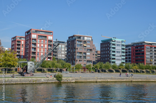 Penthouses on the banks of the Main River in Frankfurt under blue sky. An old gray container crane stands on the shore