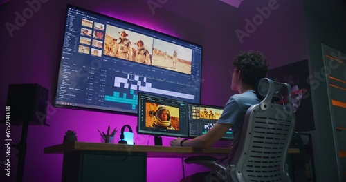 Young video maker edits movie about space mission, works at home office. Film footage and software interface with tools and sound tracks on computer and big digital screen. Concept of post production.