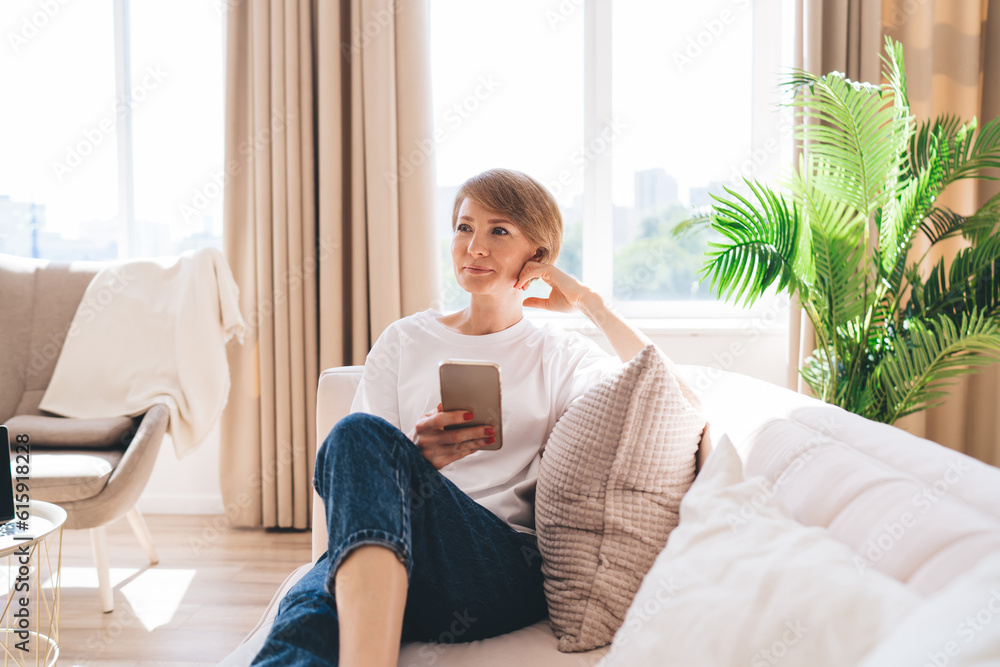 Cheerful adult woman with smartphone in modern apartment Cheerful adult woman with smartphone in modern apartment