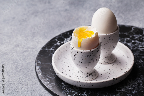 Close up view of two soft boiled eggs in eggcups on marble plate. Side view, copy space photo