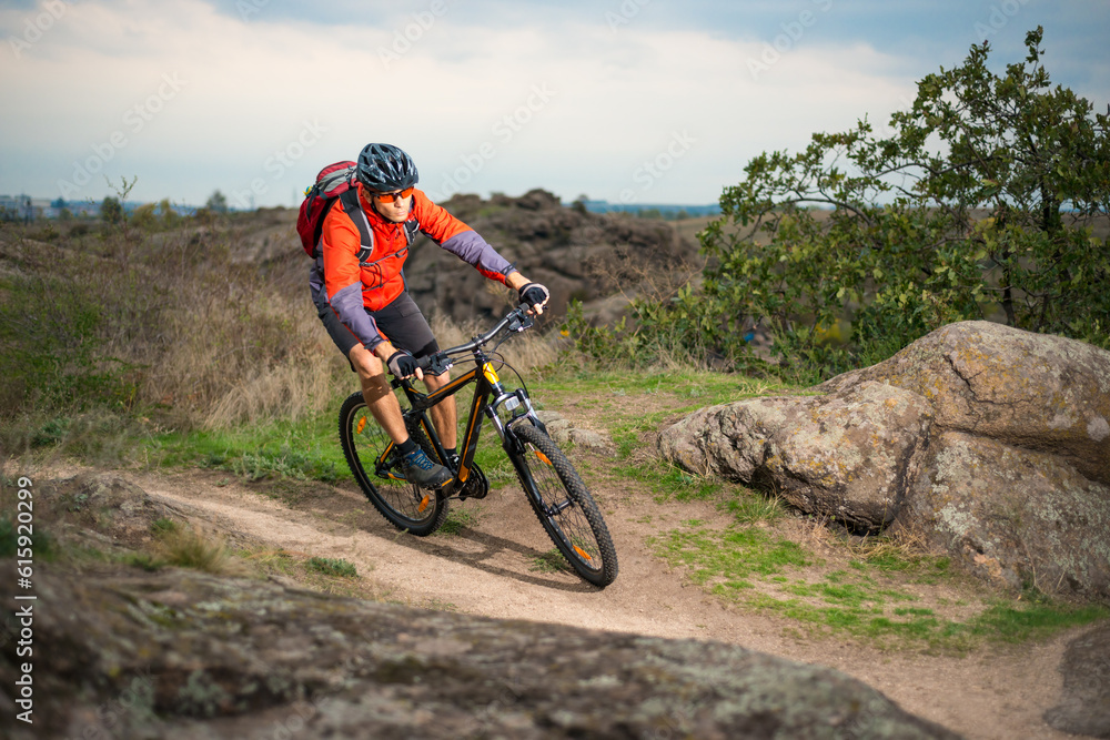 Cyclist in Red Riding the Bike on the Autumn Rocky Trail. Extreme Sport and Enduro Biking Concept.