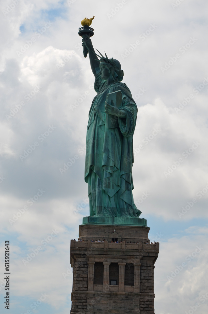 The Statue of Liberty on Liberty Island under cloudy sunny skies