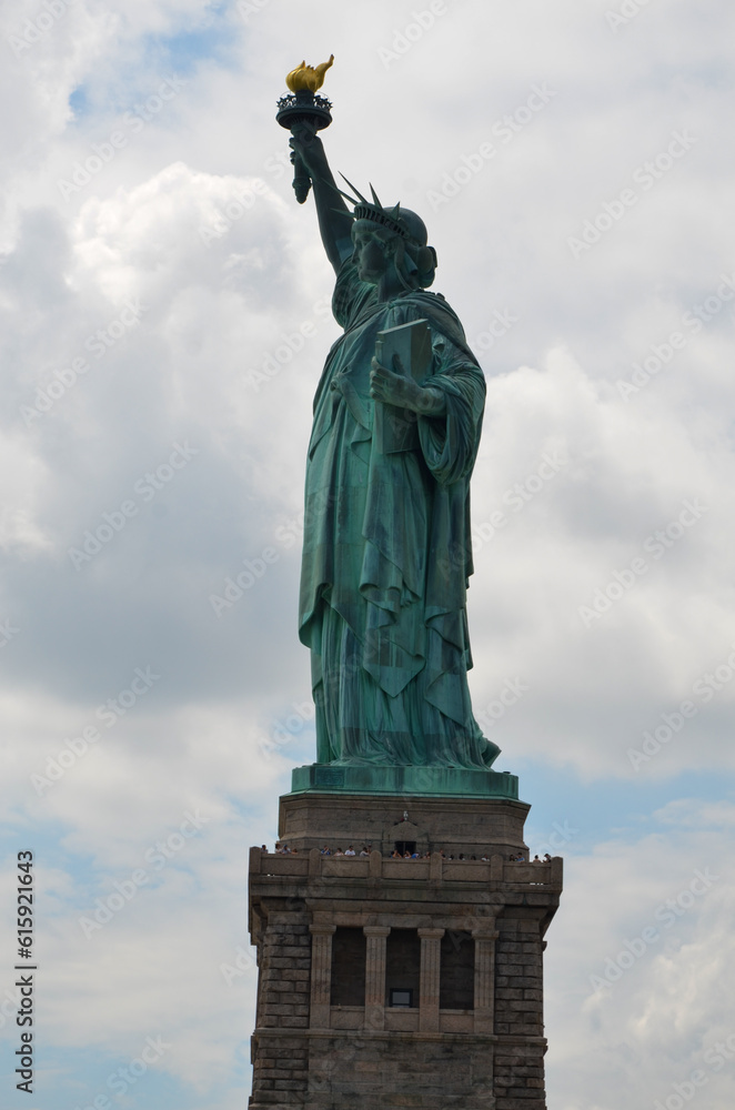 Fototapeta premium The Statue of Liberty on Liberty Island under cloudy sunny skies