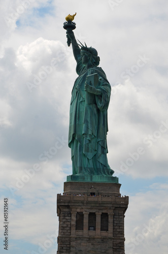 The Statue of Liberty on Liberty Island under cloudy sunny skies