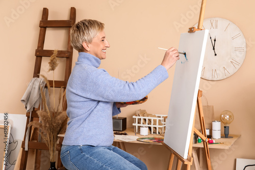 Mature female artist painting picture in workshop