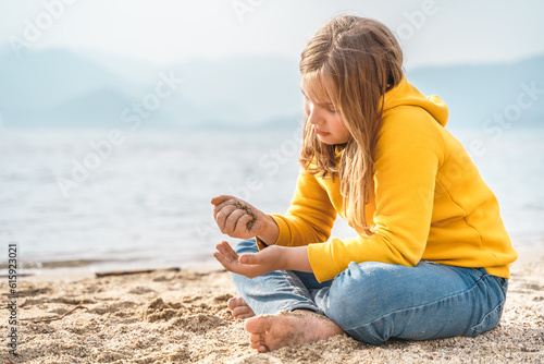 Lonely beautiful sad girl teenager sits thoughtfully on sand sea beach. Dreams,anxiety,worries about future,school friends, parents. Teen bullying, psychological problems in adolescent puberty period photo