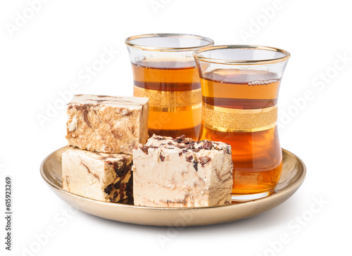 Glasses of Turkish tea and pieces of tasty marble halva on white background photo