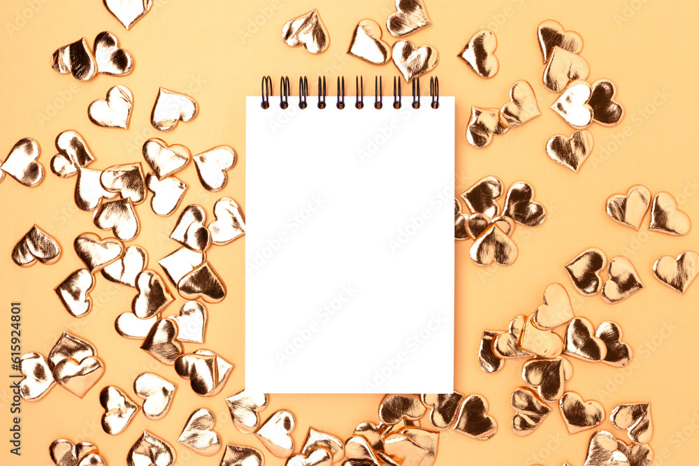 Fototapeta premium Empty notepad mockup with gold colored hearts confetti. Festive concept.
