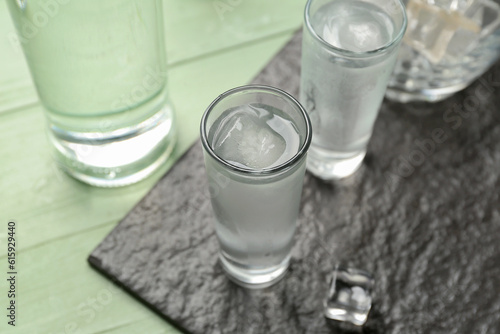 Glasses of cold vodka on green wooden background