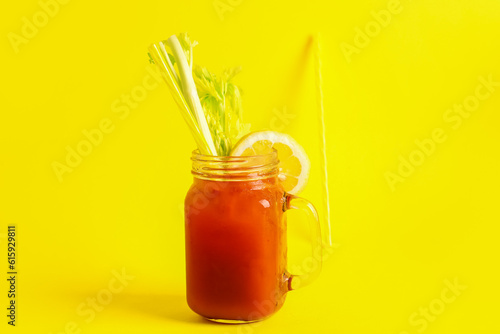 Mason jar of bloody mary with celery and lemon on yellow background © Pixel-Shot