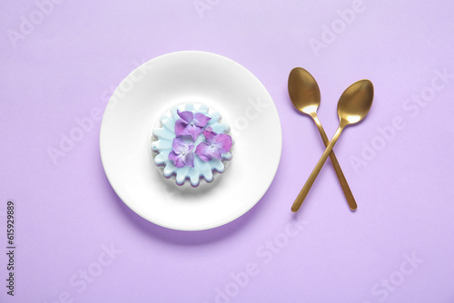 Plate of panna cotta with beautiful hydrangea flowers on lilac background