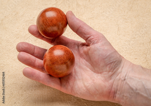 Foto male hand holding a pair of wooden Chinese medicine balls against textured paper