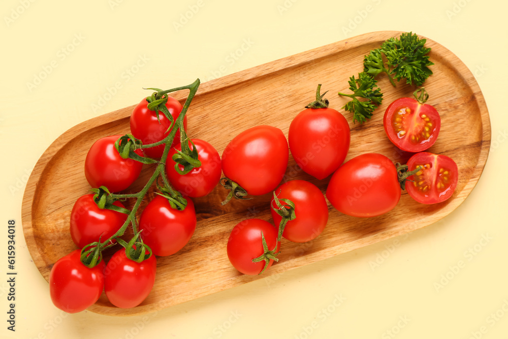 Board with fresh cherry tomatoes and parsley on yellow background Board with fresh cherry tomatoes and parsley on yellow background