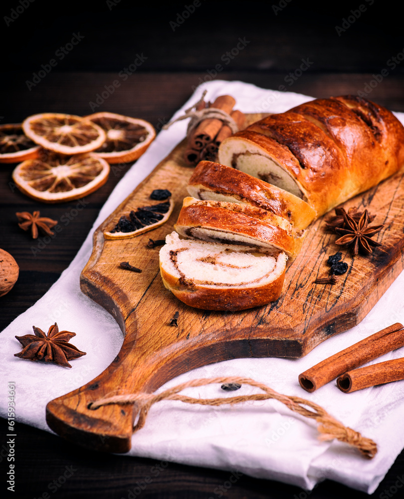 baked roll with cinnamon and nuts on a wooden board, vintage toning