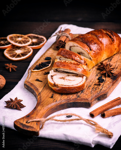 baked roll with cinnamon and nuts on a wooden board, vintage toning