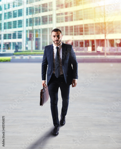 Businessman walking on the street with skyscraper background.