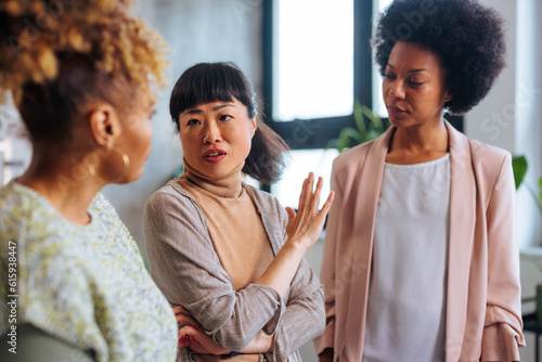 Fotografie Multiracial team of three business women having argument in office