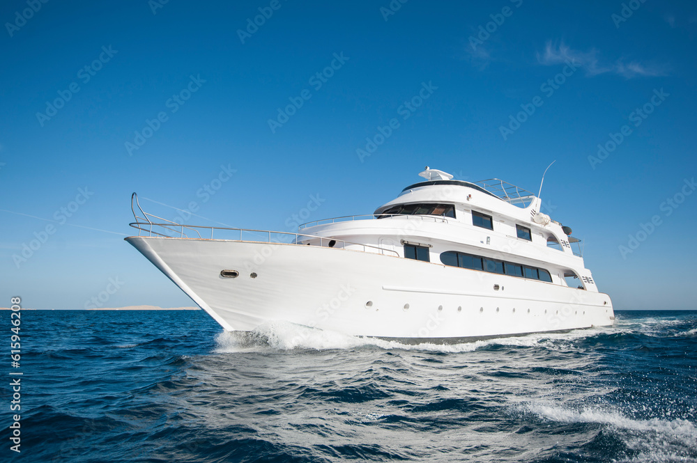 A luxury private motor yacht under way on tropical sea with bow wave