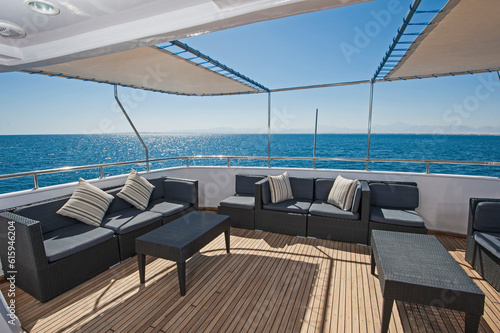 Rear teak deck of a large luxury motor yacht with chairs sofa table and tropical sea view background © Designpics