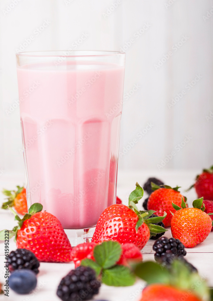 Milkshake glass with fresh summer berries smoothie on wooden background.Strwberries and raspberies with blueberries and blackberries. Milkshake glass with fresh summer berries smoothie on wooden background.Strwberries and raspberies with blueberries and blackberries.