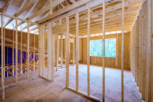 Interior of new house under construction with unfinished wooden framing beams on walls