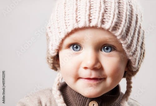 Portrait of a beautiful baby girl in a huge knitted hat. Isolated on white background.