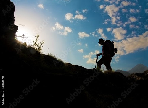Silhouette of a man hiking in mountains with backpack.