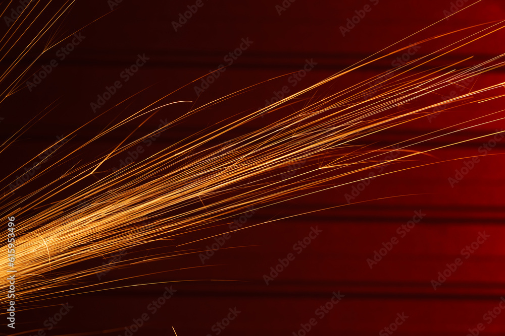 Angle grinder sparks, indoors shoot over red metal background Angle grinder sparks, indoors shoot over red metal background