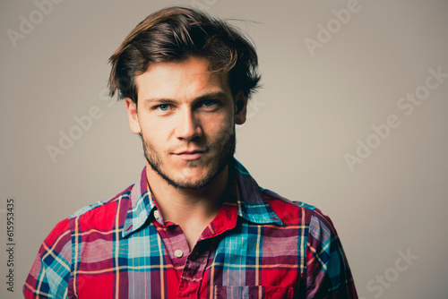 Fashion portrait of a handsome man with trendy hairstyle in a stylish shirt on light green background