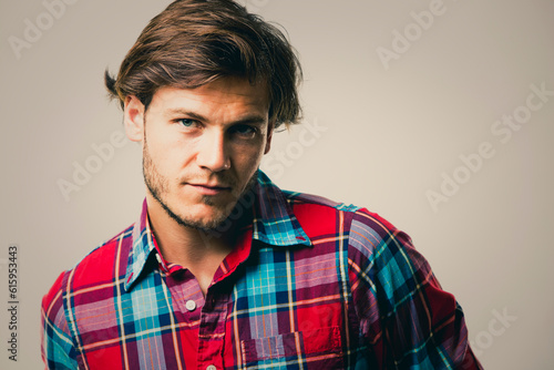 Fashion portrait of a handsome man with trendy hairstyle in a stylish shirt on light green background