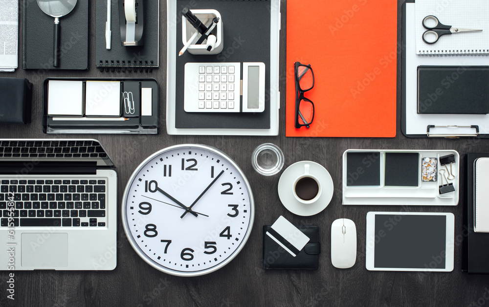 Corporate business desktop with laptop, office accessories and a clock: business productivity and deadlines concept Corporate business desktop with laptop, office accessories and a clock: business productivity and deadlines concept