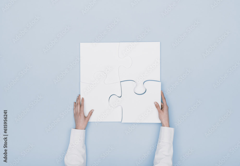 Woman assembling a jigsaw puzzle she is adding the last missing piece, solutions and challenges concept Woman assembling a jigsaw puzzle she is adding the last missing piece, solutions and challenges concept