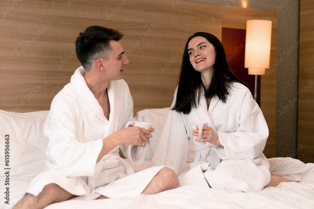 young couple on honeymoon in hotel room having breakfast in room drinking coffee happy lovers travel concept