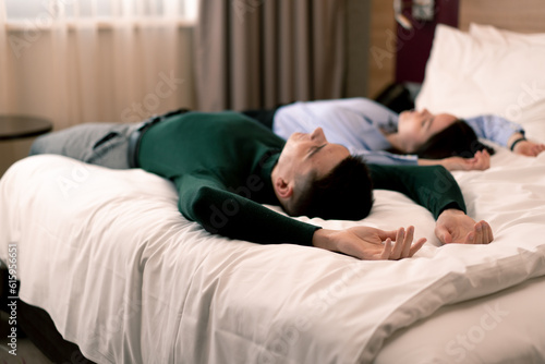 young couple in the room of a luxury hotel room lovers fall on the bed raise their hands to the top rear view travel concept