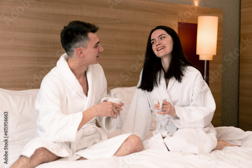 young couple on honeymoon in hotel room having breakfast in room drinking coffee happy lovers travel concept
