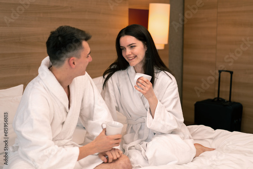 young couple on honeymoon in hotel room having breakfast in room drinking coffee happy lovers travel concept