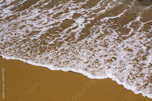 Beautiful waves with white foam on sand beach. Background.