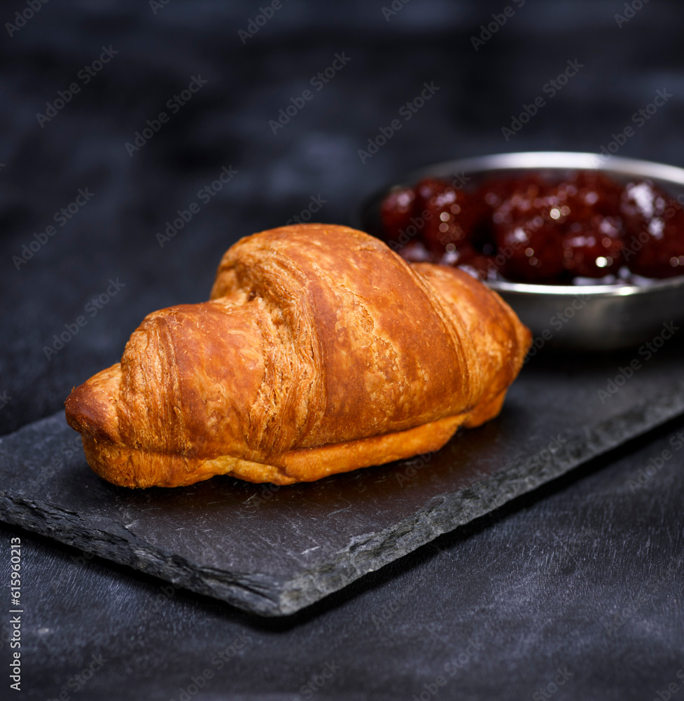 baked croissant on a black graphite background, close up baked croissant on a black graphite background, close up