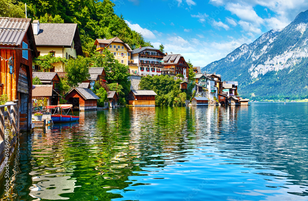Hallstatt, Austria. View to Hallstattersee Lake and Alps mountains. Ancient houses at lake banks. Summer day. Blue sky with clouds.