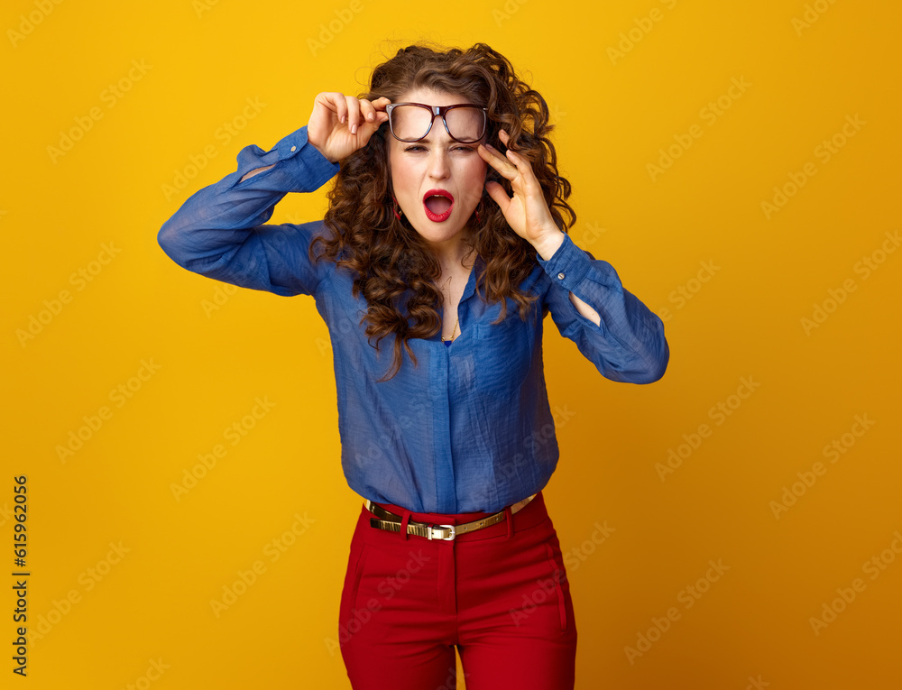 stylish woman with long wavy brunette hair in glasses squinting on yellow background stylish woman with long wavy brunette hair in glasses squinting on yellow background
