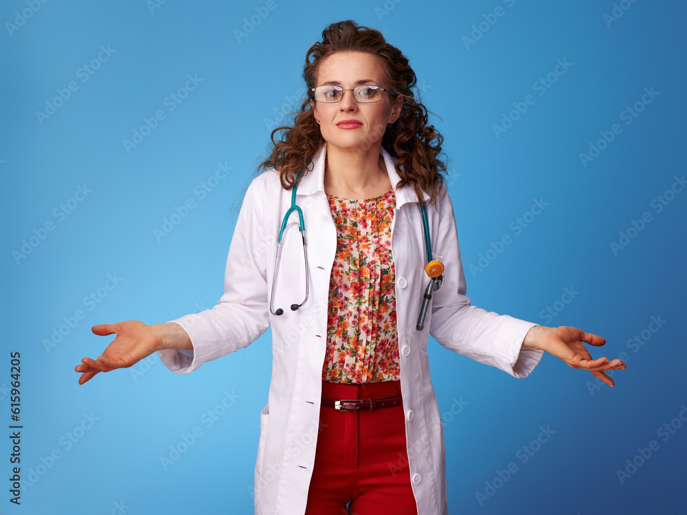paediatrist doctor in white medical robe shrugging shoulders on blue background paediatrist doctor in white medical robe shrugging shoulders on blue background