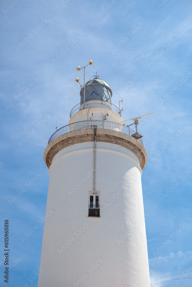 A white whitewashed lighthouse isolated over blue sky with clouds A white whitewashed lighthouse isolated over blue sky with clouds