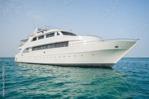 Large private luxury motor yacht boat sailing out on a tropical sea